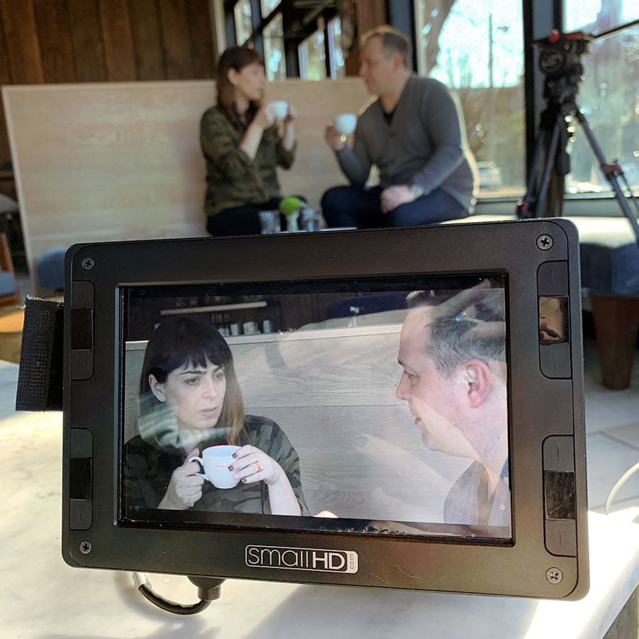 Closeup on a preview monitor during a video shoot with a couple having a discussion in a coffee shop.