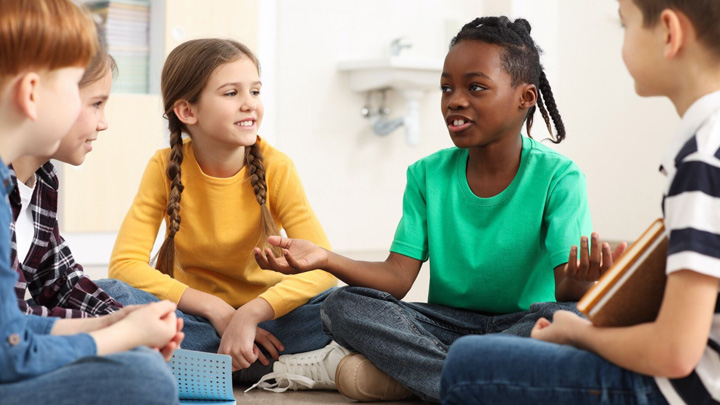 Group of young students sitting cross-legged on a floor having a discussion