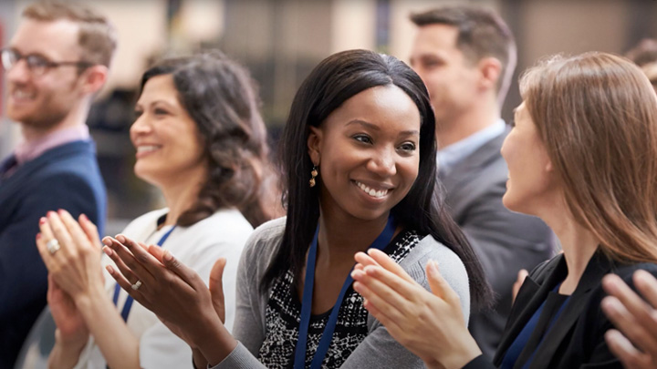 People in an audience at a conference clapping